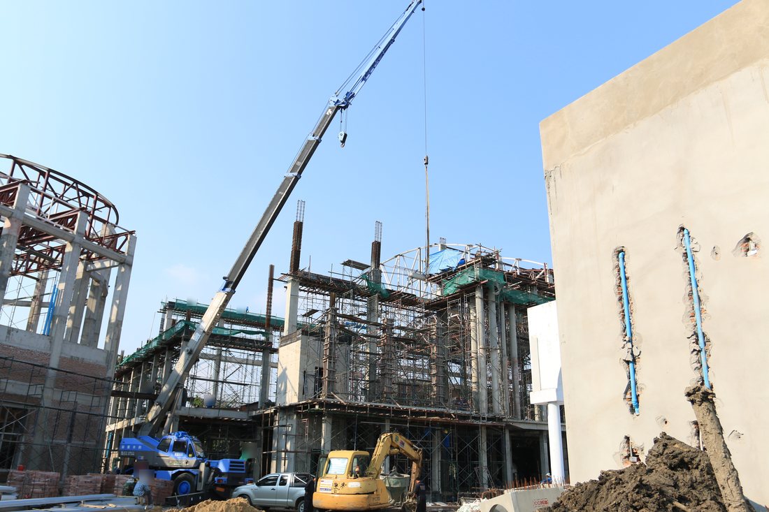 เครนล้อยางสีน้ำเงิน BIG MACHINE TRADING ทำงานหน้าอาคารเรียนโรงเรียนนานาชาติบางนาที่กำลังก่อสร้าง
