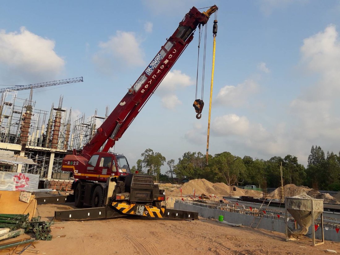 เครนล้อยาง BIG MACHINE TRADING มุมกว้างที่ไซต์ก่อสร้างวิทยาลัยเทคโนโลยีไออาร์พีซี เห็นโครงสร้างอาคารเสาและคานเรียงราย