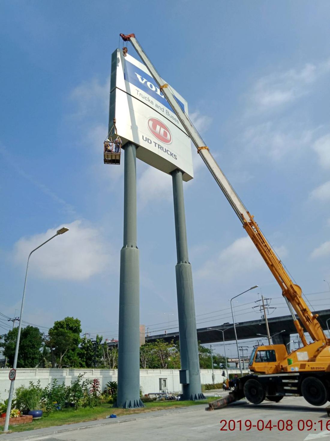 เครนยกกระเช้าคนงานขึ้นไปซ่อมป้ายโชว์รูม VOLVO Trucks และ UD Trucks บนเสาสูง 2 ต้น