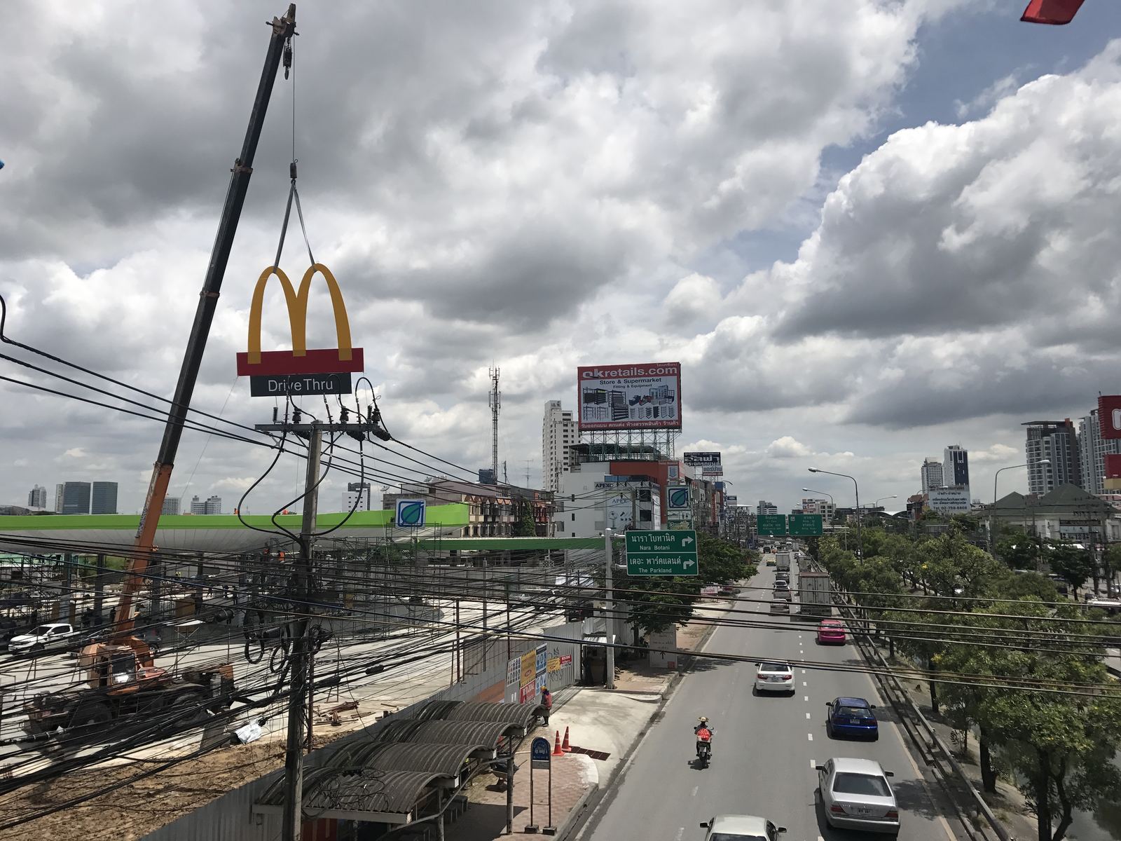 เครนยกป้ายร้านฟาสต์ฟู้ดพร้อมป้าย Drive Thru ขึ้นติดตั้งใกล้แนวสายไฟฟ้าริมถนน