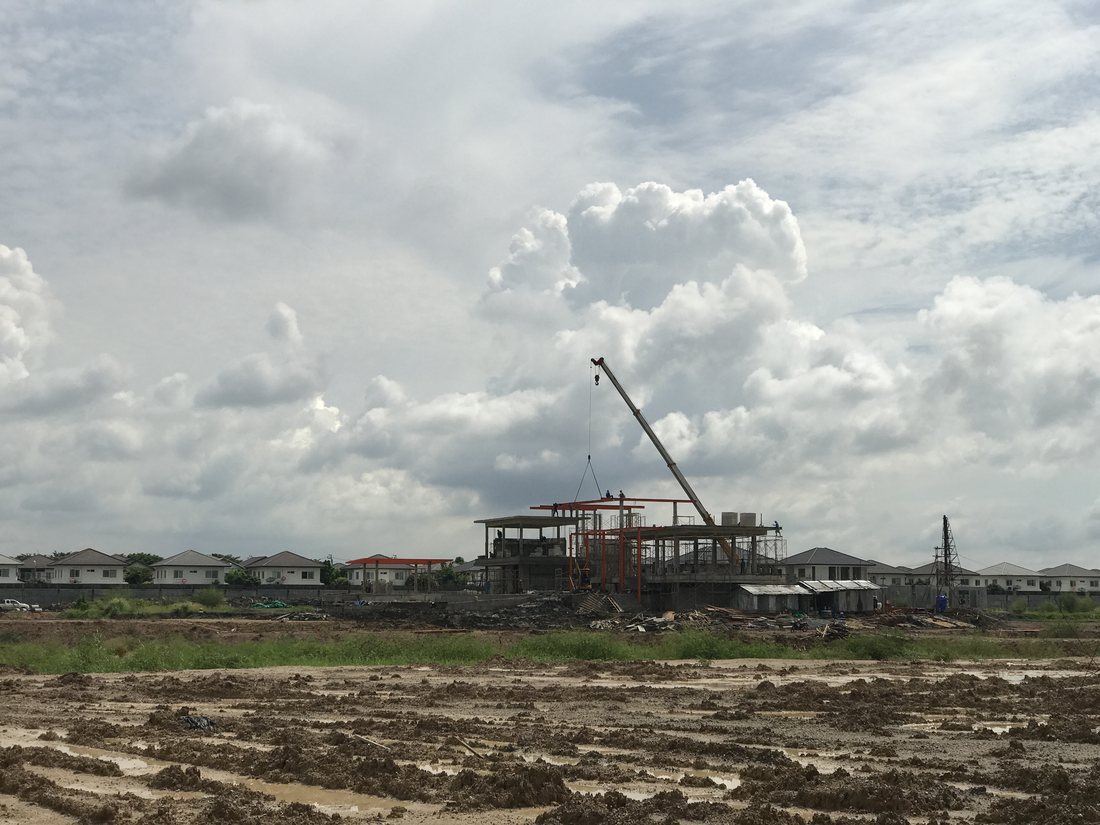 เครนล้อยาง BIG MACHINE TRADING ยกโครงสร้างเหล็กที่ไซต์ก่อสร้างมัณฑนา อ่อนนุช-วงแหวน 5 มองเห็นบ้านเดี่ยวโดยรอบ