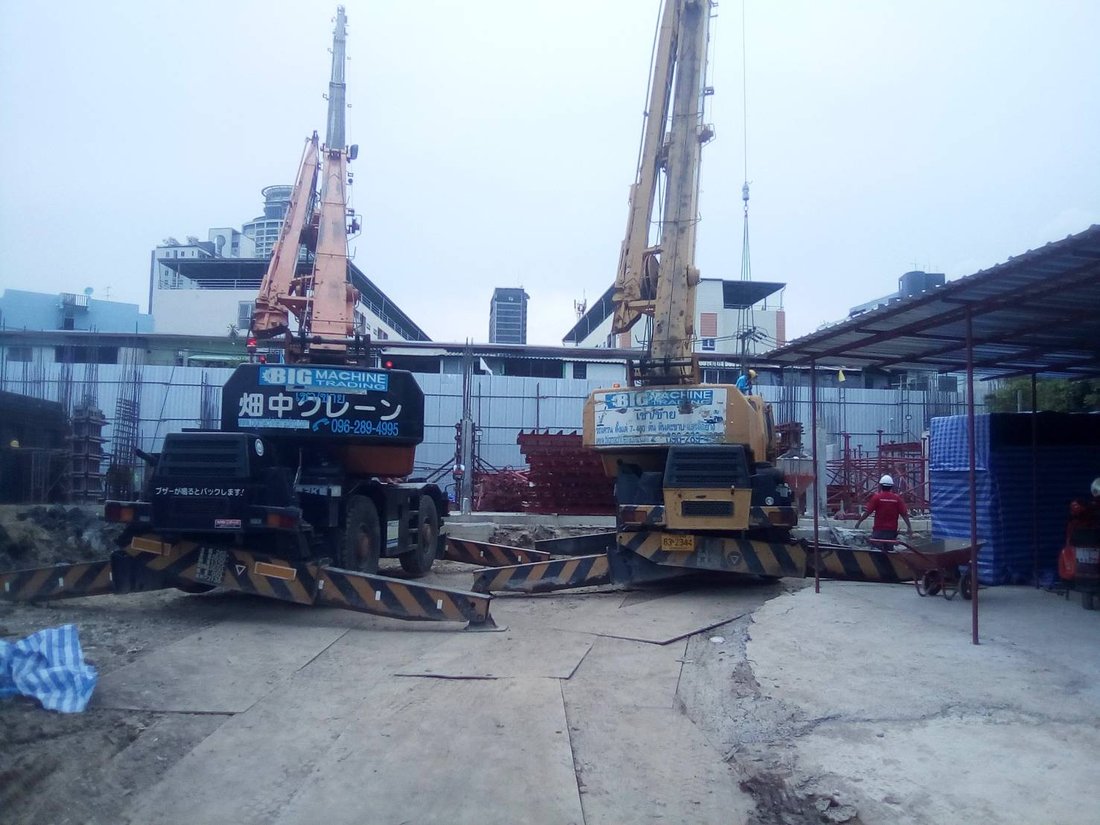 เครนล้อยาง BIG MACHINE TRADING สองคันจอดเรียงกันที่ไซต์ก่อสร้าง The Nest Sukhumvit 71 เห็นป้ายบริษัทชัดเจน
