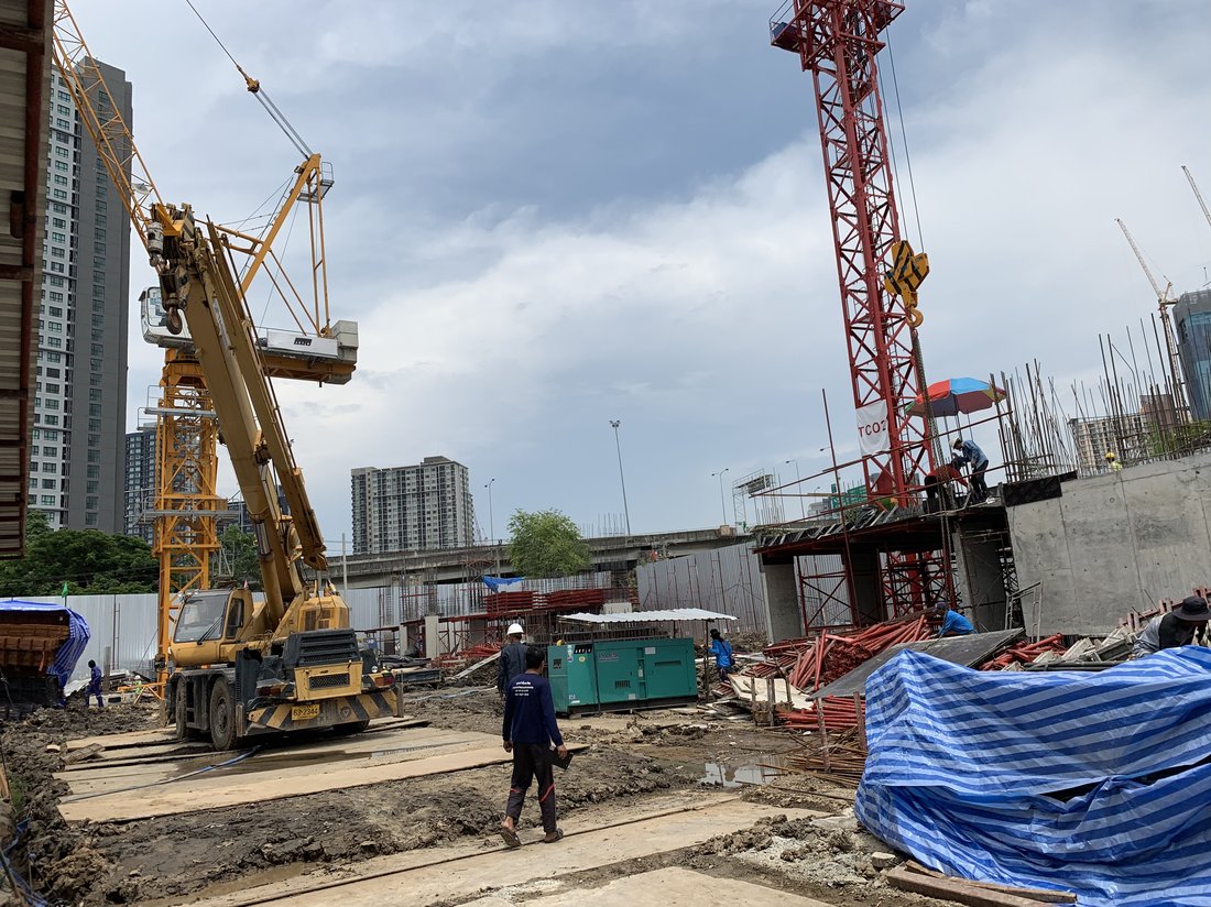 เครนล้อยาง BIG MACHINE TRADING ทำงานควบคู่กับทาวเวอร์เครนสีแดงที่ไซต์ก่อสร้าง The Nest Sukhumvit 71 เห็นทีมงานตรวจสอบหน้างาน