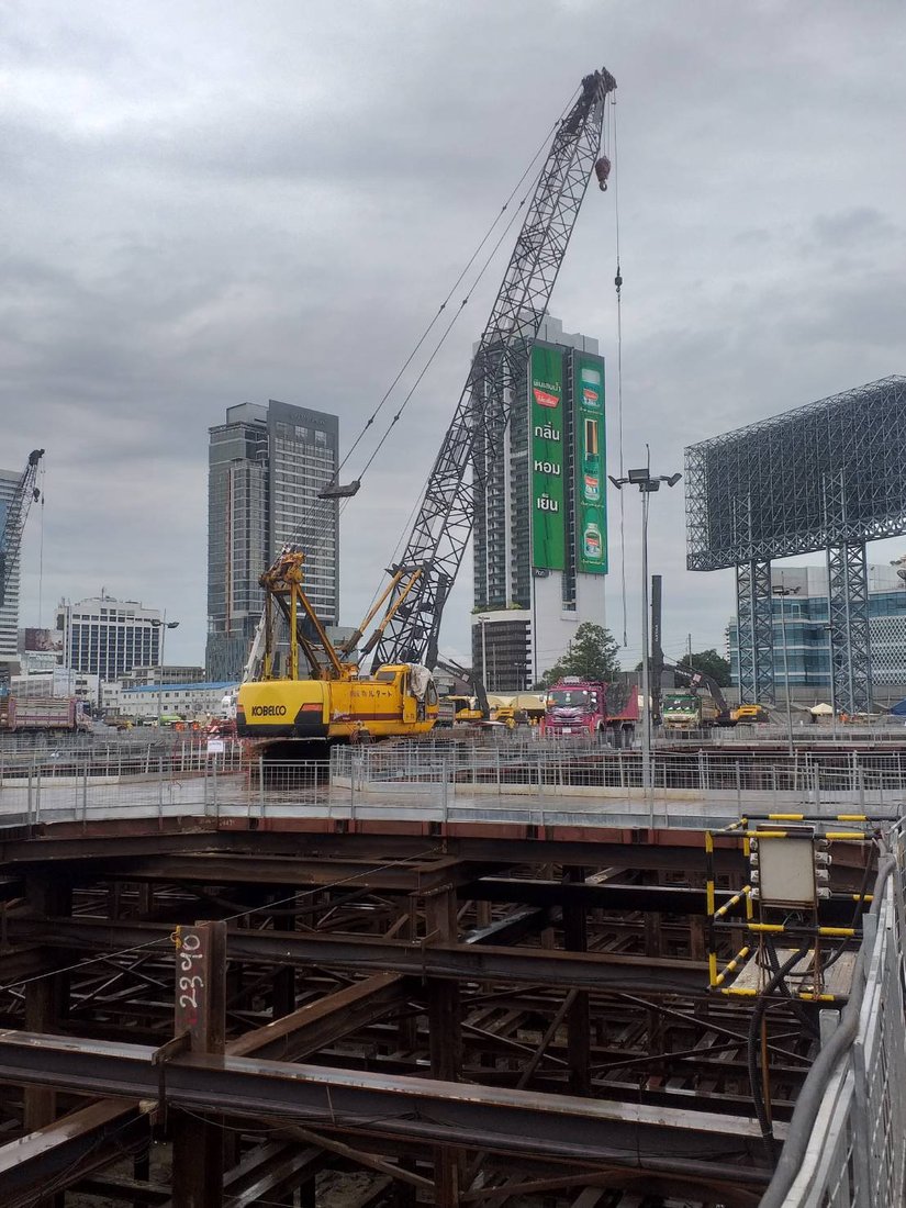 เครนตีนตะขาบ KOBELCO ของ BIG MACHINE TRADING ทำงานที่ไซต์ก่อสร้าง One Bangkok เห็นป้ายโฆษณาขนาดใหญ่และตึกสูงด้านหลัง
