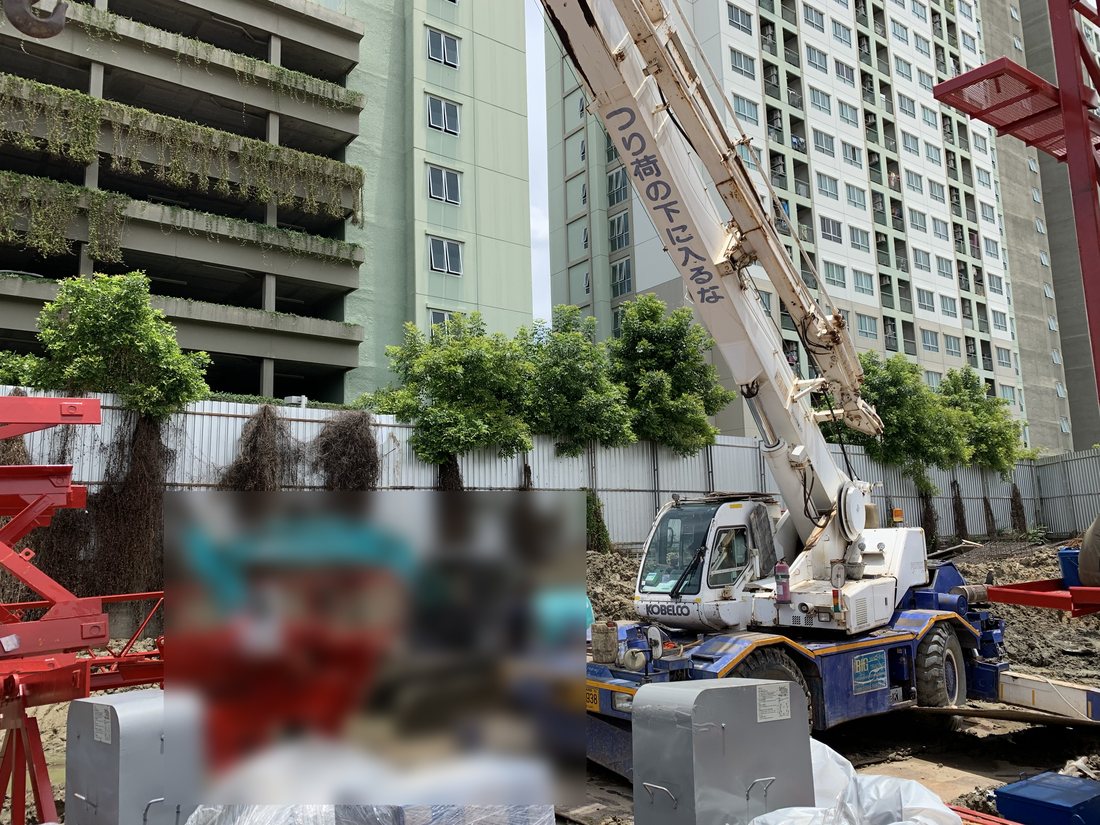 เครนล้อยาง BIG MACHINE TRADING ทำงานหน้าไซต์ก่อสร้างคอนโดมิเนียมย่านอ่อนนุช มองเห็นอาคารที่พักอาศัยด้านหลัง
