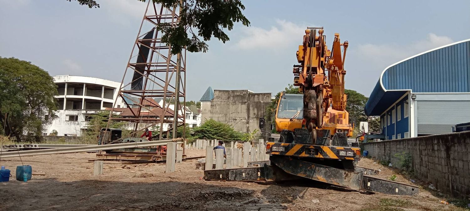 เครนของ BIG MACHINE TRADING หน้างานฐานราก อีกพื้นที่หนึ่ง เห็นโครงปั้นจั่นและเสาเข็มคอนกรีตวางเตรียมไว้