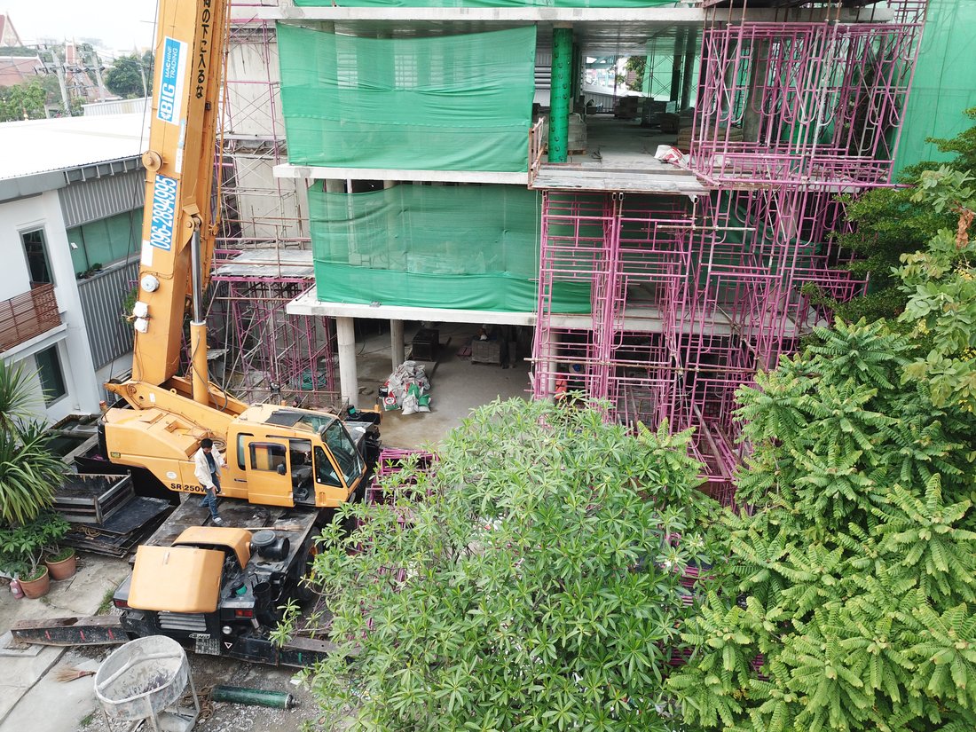 เครนล้อยาง BIG MACHINE TRADING ทำงานที่ไซต์ก่อสร้างอาคารสำนักงาน 5 ชั้น ย่านรามคำแหง เห็นโครงสร้างอาคารและนั่งร้านรอบตัว