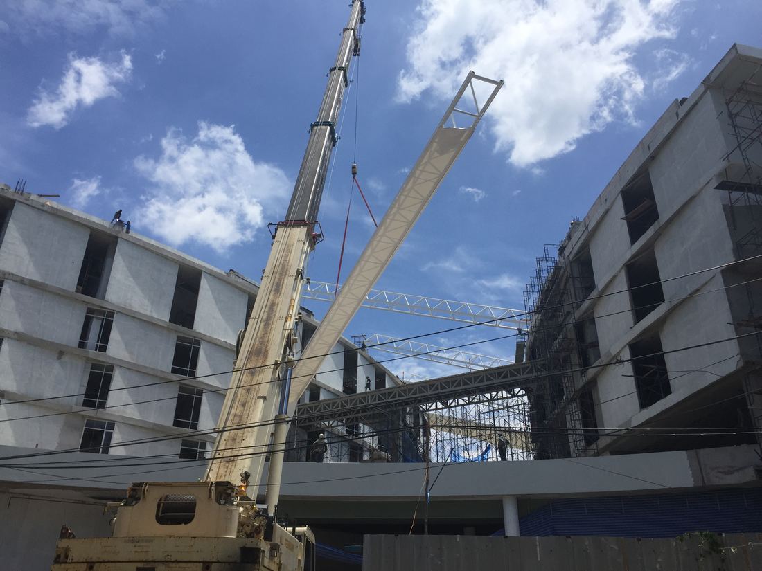 เครนตีนตะขาบสีขาวขนาด 200 ตันของ BIG MACHINE TRADING กำลังยกโครงหลังคาผ้าใบขนาดใหญ่ระหว่างอาคารมหาวิทยาลัยรังสิต
