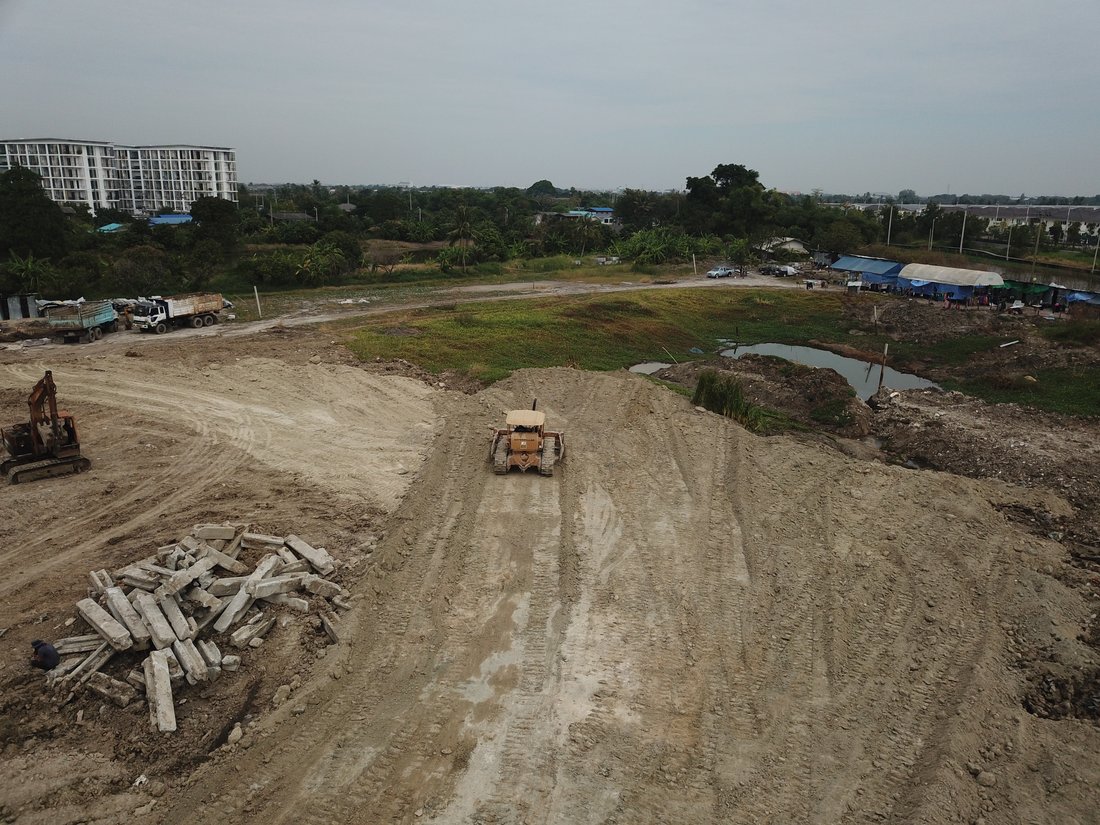 รถดันดิน CATERPILLAR ของ BIG MACHINE TRADING ทำงานปรับพื้นที่ก่อสร้างรีสอร์ตเฟส 2 มุมสูงจากโดรน เห็นกองเศษคอนกรีตและรถขุดข้างเคียง