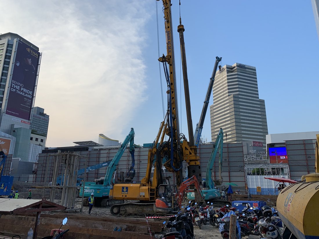 ไซต์ก่อสร้าง SIAMSCAPE เห็นเครื่องเจาะเสาเข็ม BAUER BC 24H และรถขุด KOBELCO ทำงานร่วมกัน เห็นตึกสูงสยามพารากอนด้านหลัง
