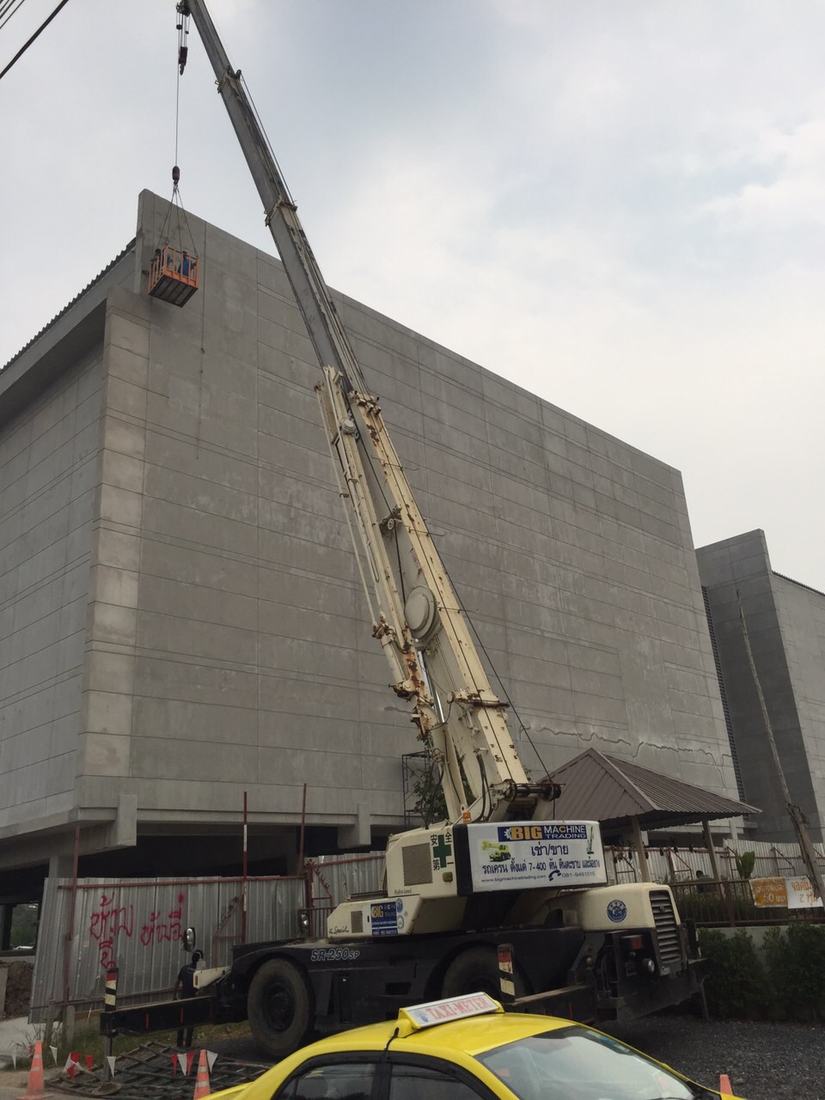 เครนของ BIG MACHINE TRADING ยกกระเช้าขึ้นไปทำงานบนหลังคาอาคารคอนกรีตที่สร้างเสร็จแล้ว