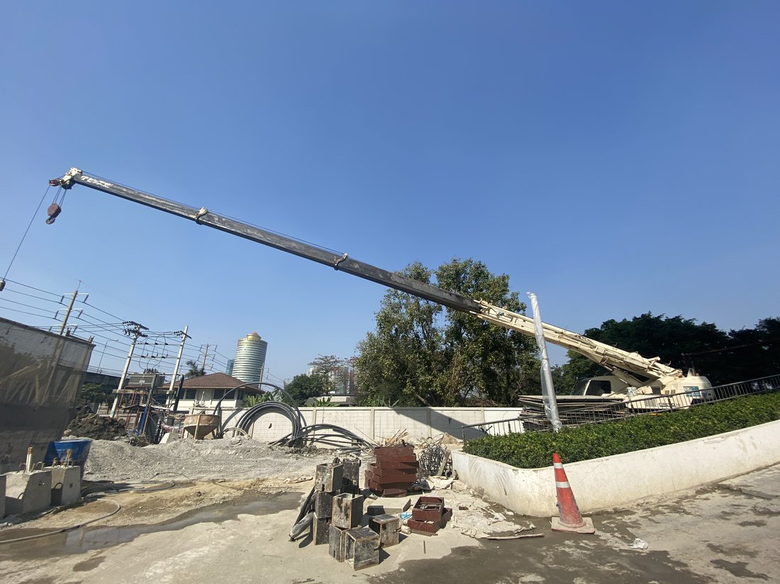 เครนล้อยาง BIG MACHINE TRADING ทำงานที่ไซต์ก่อสร้างศุภาลัย ริวา แกรนด์ ช่วงเย็น เห็นตึกสูงย่านพระราม 3 ด้านหลัง