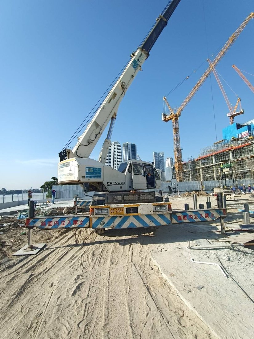 เครนล้อยาง BIG MACHINE TRADING ทำงานที่ไซต์ก่อสร้างศุภาลัย ริวา แกรนด์ ริมแม่น้ำเจ้าพระยา เห็นทาวเวอร์เครนของโครงการข้างเคียงด้านหลัง