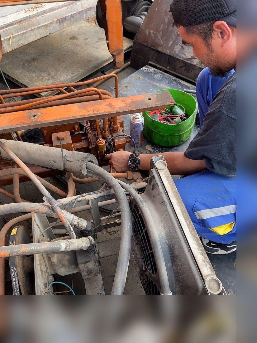 ช่างของ BIG MACHINE TRADING กำลังเปลี่ยนโซลินอยสวิงบนบล็อกวาล์วไฮดรอลิกของเครน