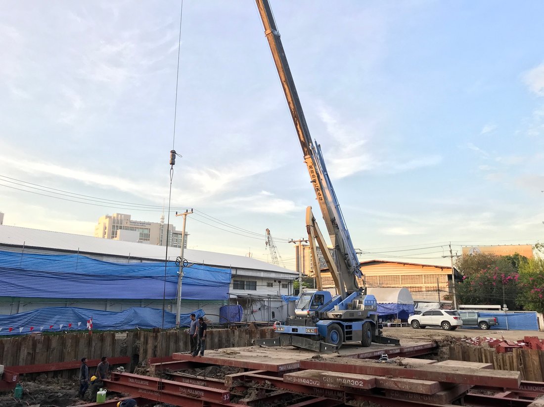 เครนล้อยาง BIG MACHINE TRADING ทำงานที่ไซต์ก่อสร้างสำนักงานเศรษฐกิจและวัฒนธรรมไทเป ช่วงเย็น เห็นอาคารสำนักงานและโรงพยาบาลด้านหลัง