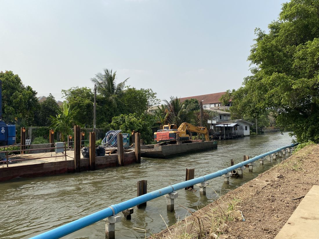 รถขุดทำงานบนโป๊ะเรือกลางคลองแคบในเขตธนบุรี