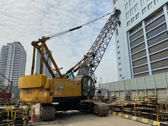 เครนตีนตะขาบ Kobelco หน้าไซต์งานก่อสร้างกลางเมือง