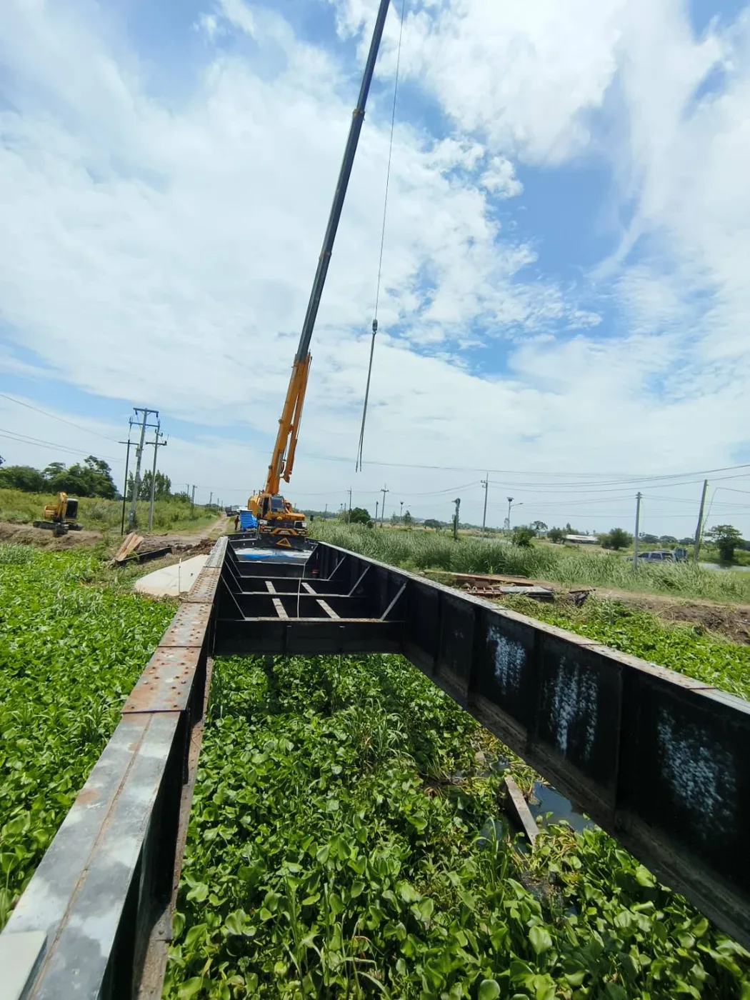 เครนยกโครงเหล็กสะพานความยาวข้ามพื้นที่เกษตรกรรม